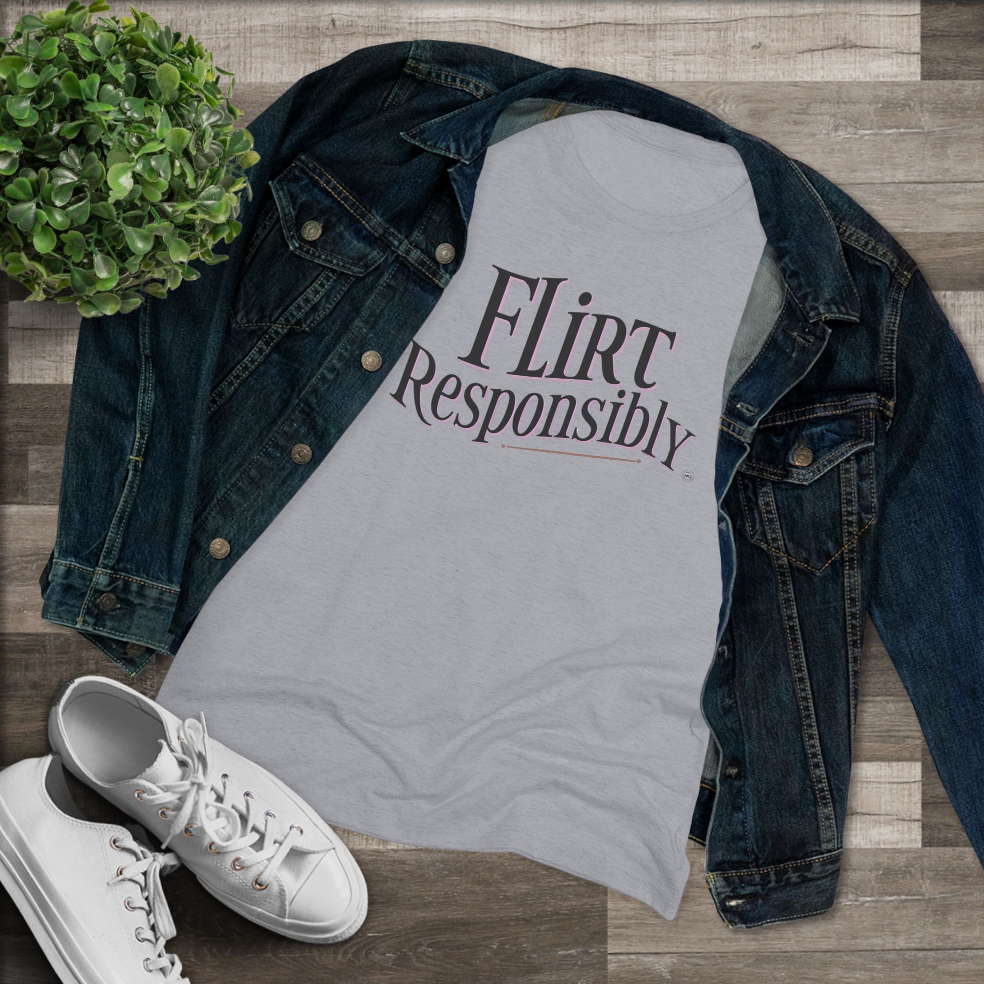 Gray t-shirt with 'Flirt Responsibly' text, denim jacket, and white sneakers on a wooden surface.