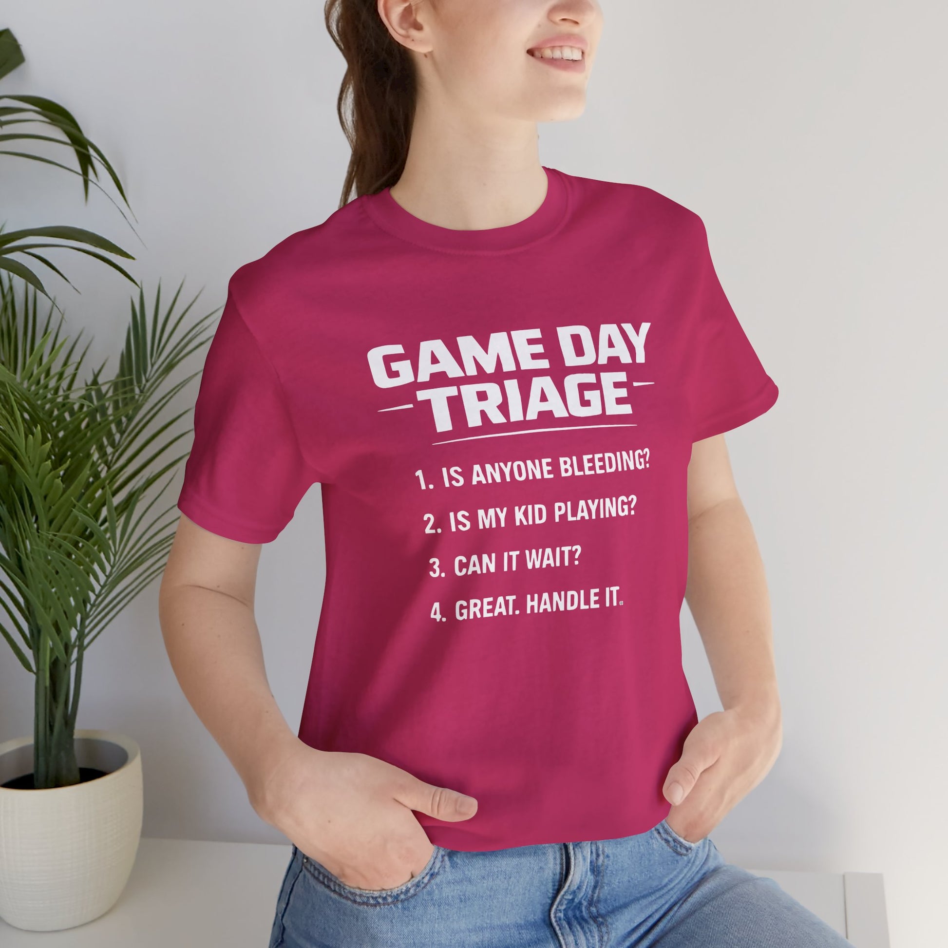 Person wearing a pink t-shirt with 'Game Day Triage' text, standing indoors.