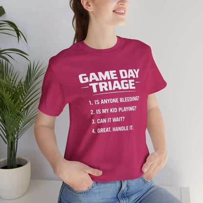 Person wearing a pink t-shirt with 'Game Day Triage' text, standing indoors.