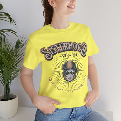 Yellow t-shirt featuring a vintage-style graphic with the words “Sisterhood Elevates” above an illustrated helmeted figure, with radiating lines and the phrase “Lifting Each Other to Greater Heights” below.