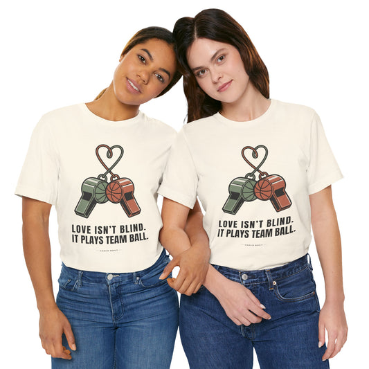 Love Isn’t Blind — It Plays Team Ball Tee (Whistle Heart)