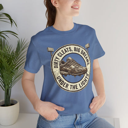 Person wearing a blue t-shirt with a graphic design and text, standing indoors next to a plant.
