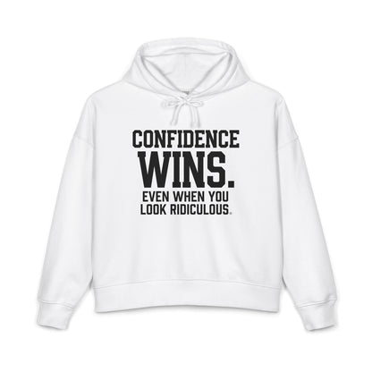 A white cropped hoodie with black text on the front reading 'CONFIDENCE WINS. EVEN WHEN YOU LOOK RIDICULOUS.